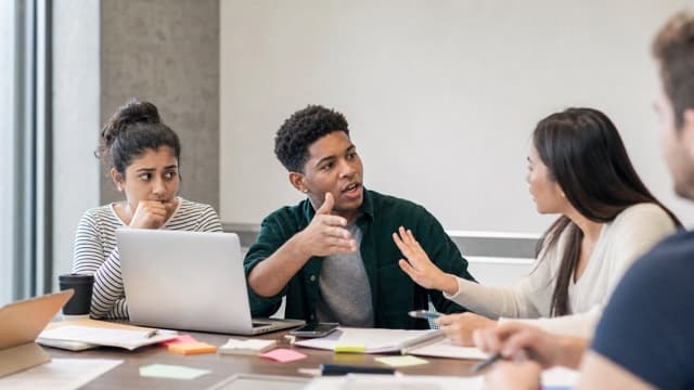 A student group manages an interrupting teammate during a project meeting.