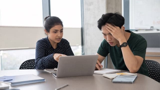 Students review a possible research data error on a laptop.