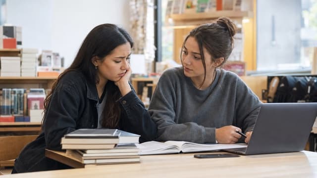 A student listens supportively to a classmate worried about course materials.